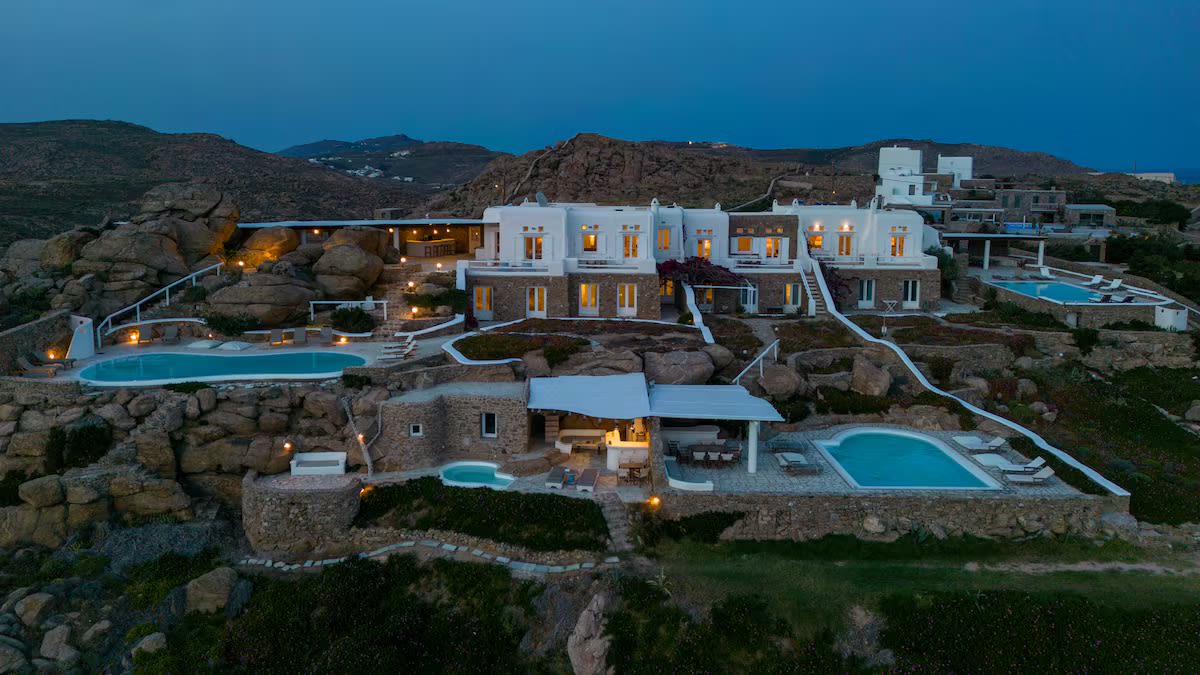 The villas at dusk, lit up on the hill above the rocks