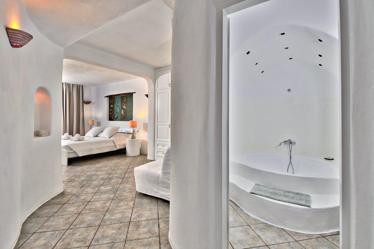 A bedroom with a tub in a whitewashed alcove